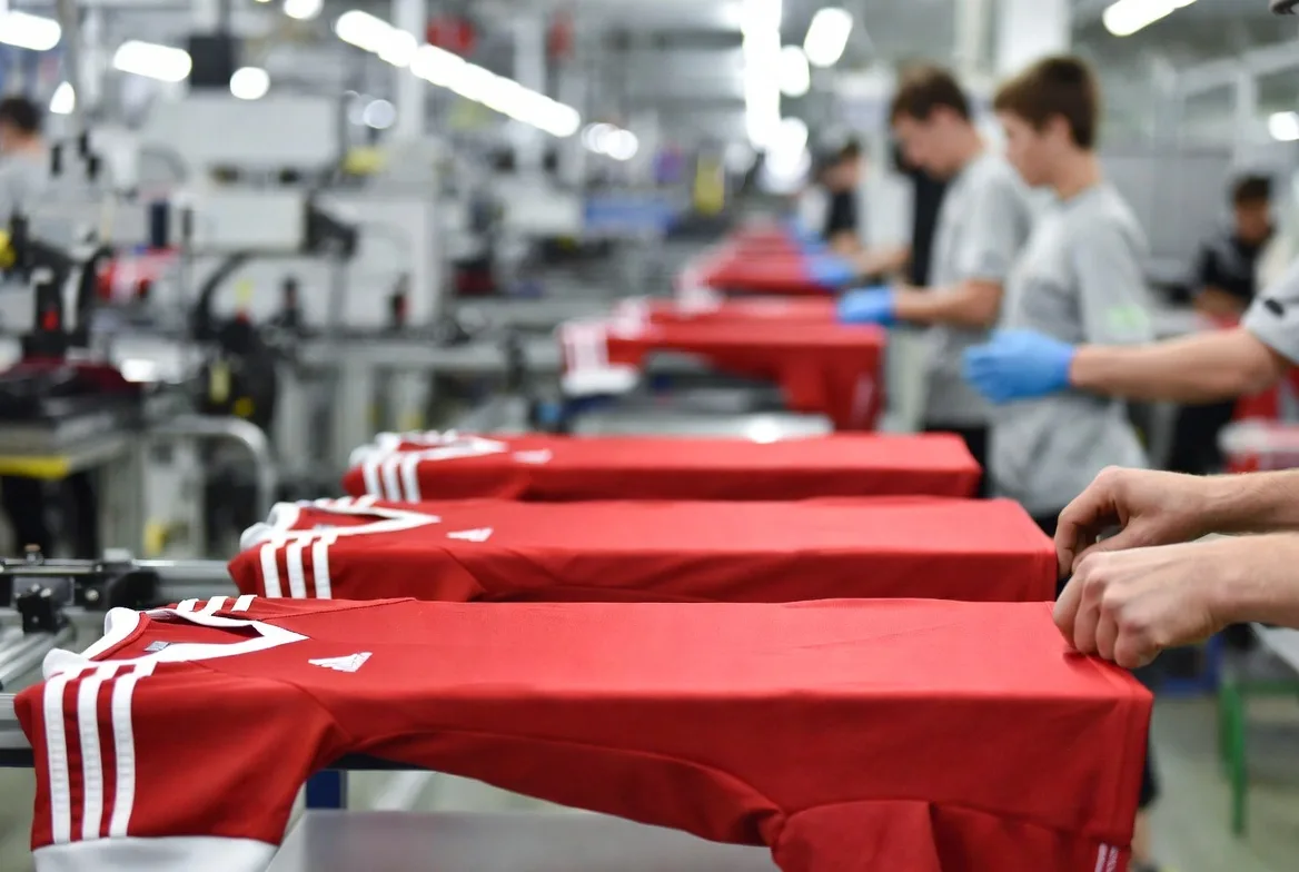 BWA Sports design team reviewing red soccer jerseys on the production line