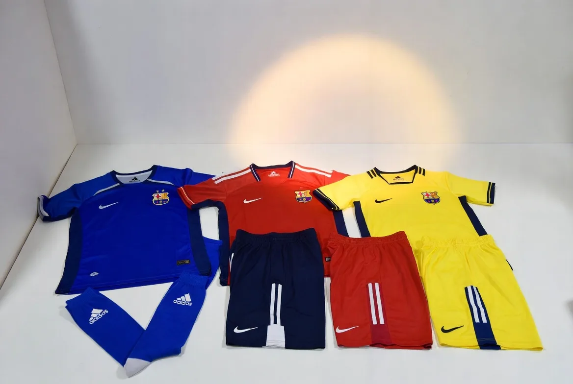 BWA Sports quality team inspecting red, blue and yellow full soccer kits laid flat